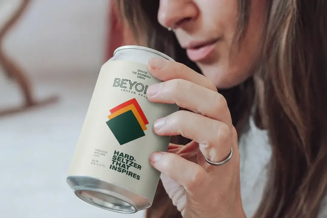 Lady holding a Beyond beer can mockup by Adverz media